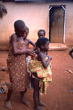 30. Older girl helping younger girl to wrap baby on her back